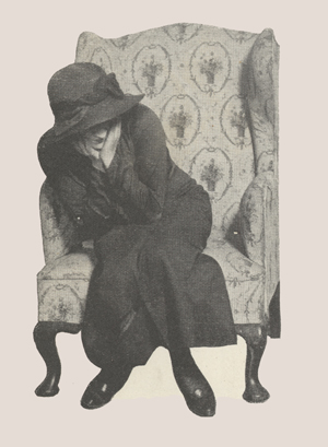 A woman sitting in a chair with her face in her hands.