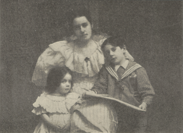Studio portrait of Mrs. Nevin seated with her daughter Doris leaning against her on her right and her son Paul leaning against her on her left holding a large piece of paper in his hands