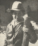 Photograph of Willa Cather wearing a western-style hat and holding a large stick of wood.