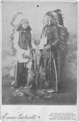 Two Native American men wearing traditional regalia