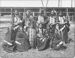 Nine Native American men and two children in traditional regalia