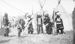 Native Americans in traditional regalia beside tipis